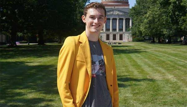 Ethan R. King ’27 wearing yellow blazer in quad in front of Rush Rhees library